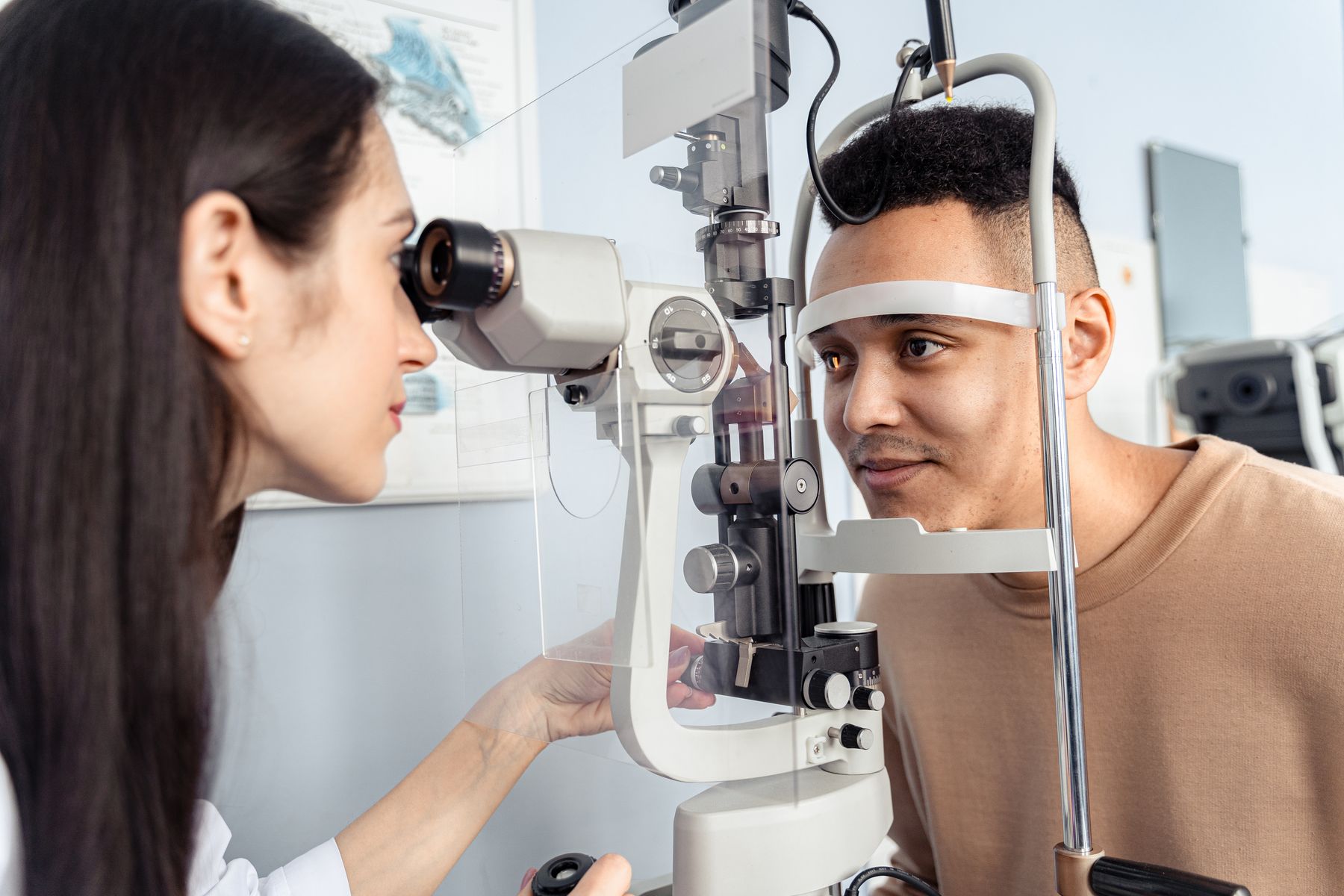 An eye-care professional examining a patient with a slit lamp
